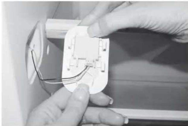 Close-up of hands installing or adjusting a white electrical socket with wires (no visible text or symbols)