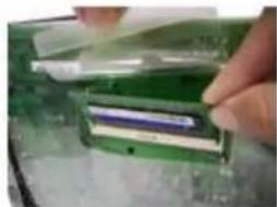 Close-up of a hand inserting a plastic component into a green plastic housing (no visible text or symbols)