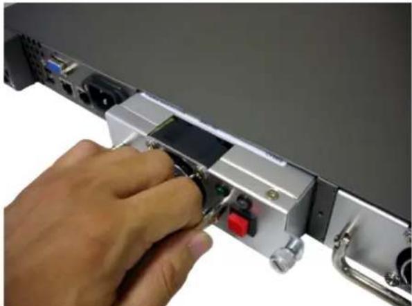 Hand inserting a USB into a server rack (no visible text or symbols)