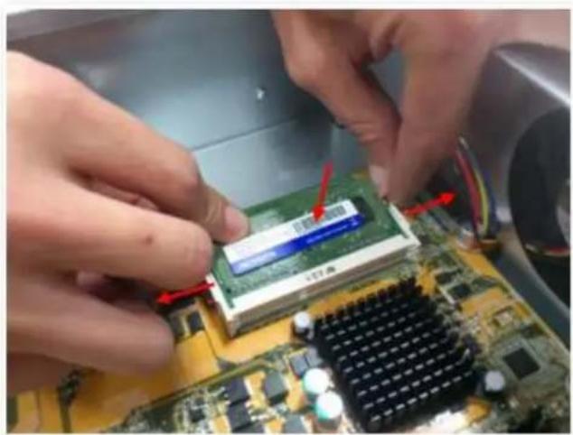 Close-up of hands installing a green RAM module on a computer motherboard, with red arrows indicating component alignment (no text or symbols visible)