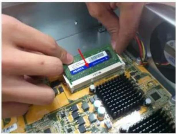 Close-up of hands installing a green RAM module on a computer motherboard (no visible text or symbols)