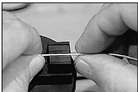 Close-up of hands tying a string on a dark mechanical component (no visible text or symbols)