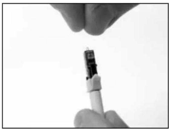 Close-up of a hand holding a small medical or laboratory device, possibly a syringe or pipette, against a plain background (no visible text or symbols)