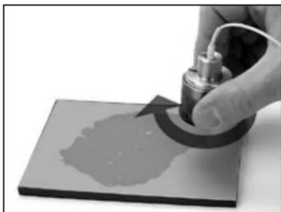 Close-up of a hand using a mechanical tool to press or print a surface (no text or symbols visible)