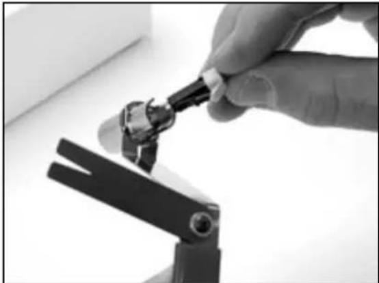 Close-up of a hand using a tool to adjust or install a mechanical component (no visible text or symbols)