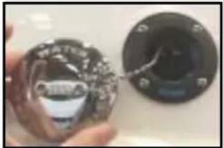 Close-up of a hand holding a small electronic device with a lens, next to a circular black component (no visible text or symbols)