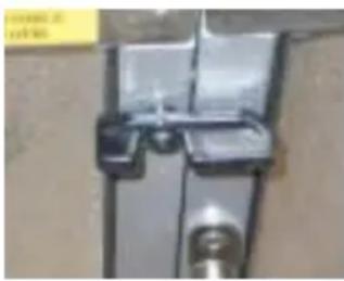 Close-up of a metallic bracket or clamp with a small cylindrical component attached (no visible text or symbols)
