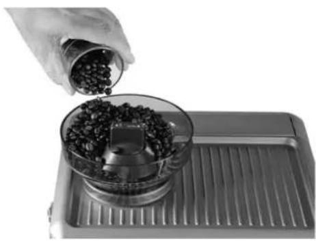 Hand pouring coffee beans into a glass bowl on a metal tray (no text or symbols visible)