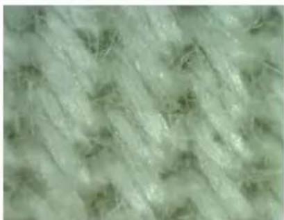 Close-up of a textured fabric with light green and beige fibers (no text or symbols).