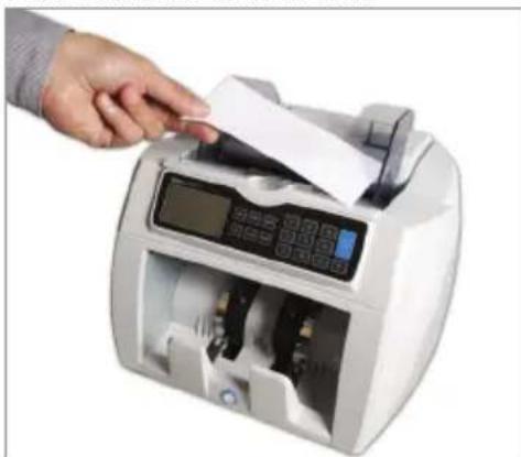 Hand inserting a document into a digital currency counter (no visible text or symbols)