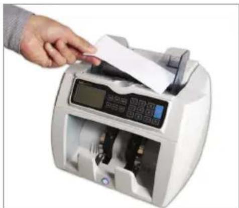 Hand inserting a document into a digital currency counter (no visible text or symbols)