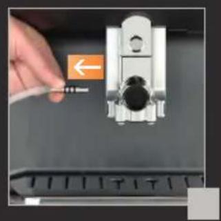 Close-up of a hand holding a small electronic device with an orange arrow pointing to it, next to a keyboard (no visible text or symbols)