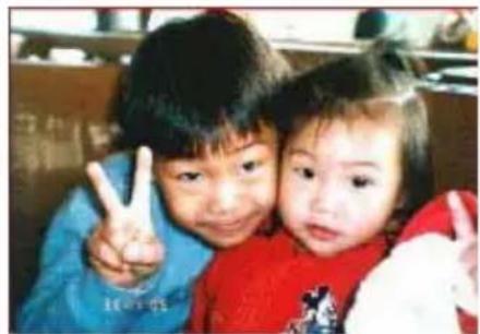 Two children making peace signs together, one adult in blue and one child in red (no visible text or symbols)