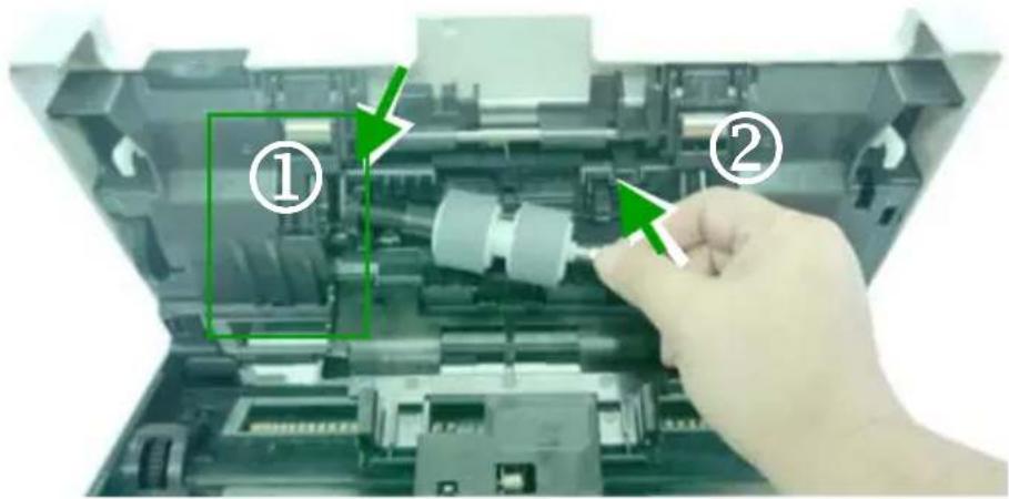 Photo of a printer internal structure with labeled parts, showing hand operating a component and green arrows indicating assembly steps.