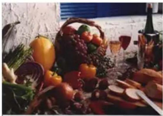 Still life arrangement of assorted fruits and vegetables including a basket, wine bottle, and glass (no text or symbols visible)