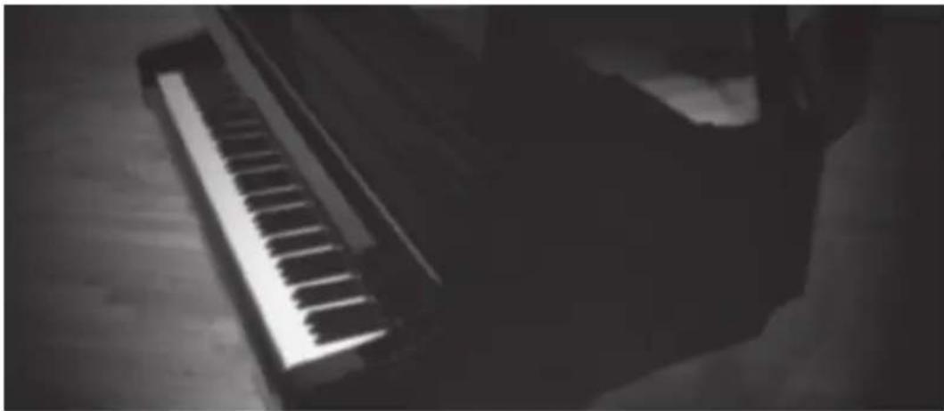 Silhouette of a hand holding a small electronic keyboard on a wooden floor (no text or symbols visible)