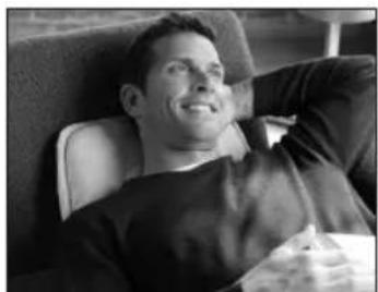 Black-and-white photo of a man sitting in a chair, looking down with hand on chin (no visible text or symbols)