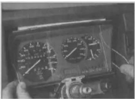 Close-up of hands holding a multimeter with dual dials and measurement scales, showing readings in meters and seconds.