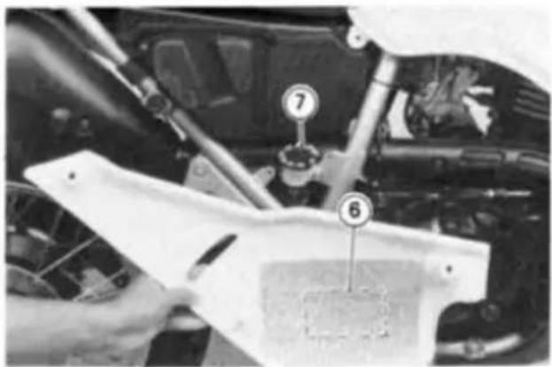 Close-up of a car engine bay with numbered parts labeled 6 and 7, showing mechanical components and wiring.