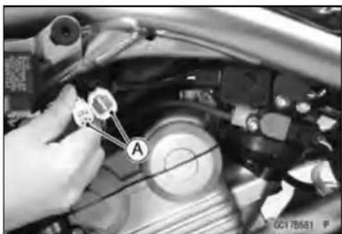 Close-up of a car engine component with labeled parts and a hand pointing to a component labeled 'A'