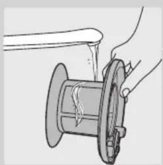 Illustration of a hand pouring liquid into a mechanical component (no text or symbols).
