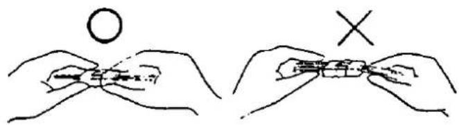 Diagram showing two hand positions: one with a circle and the other with an 'X' symbol, illustrating a folding or folding process.