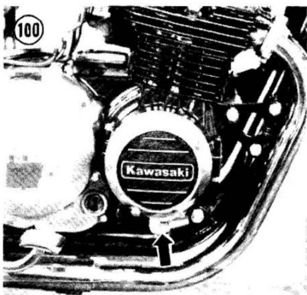 Close-up of a motorcycle engine component with visible brand mark 'Kawasaki' and number 100, no readable text or symbols beyond the label.