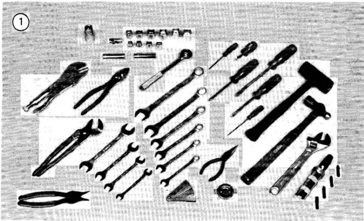 Collection of various hand tools and pliers arranged on a textured surface (no text or symbols visible)