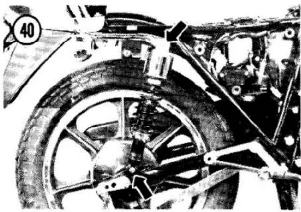 Close-up of a vintage motorcycle wheel assembly with visible tire, suspension components, and frame (no text or symbols)