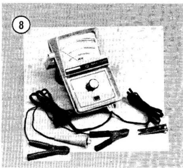 Black-and-white photo of a multimeter with wires and probes, no visible text or symbols on the device itself.