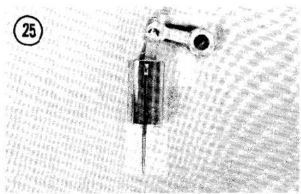 Close-up of a mechanical device with a cylindrical component and a rectangular base, placed on a textured surface (no visible text or symbols)