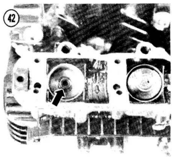 Close-up of an engine cylinder head with a black arrow pointing to a specific component (no visible text or symbols)