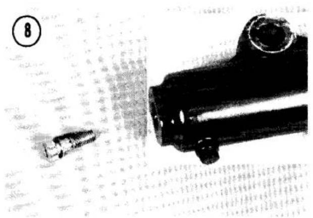 Black-and-white photo showing a handgun and a moving pencil on a textured surface (no visible text or symbols)