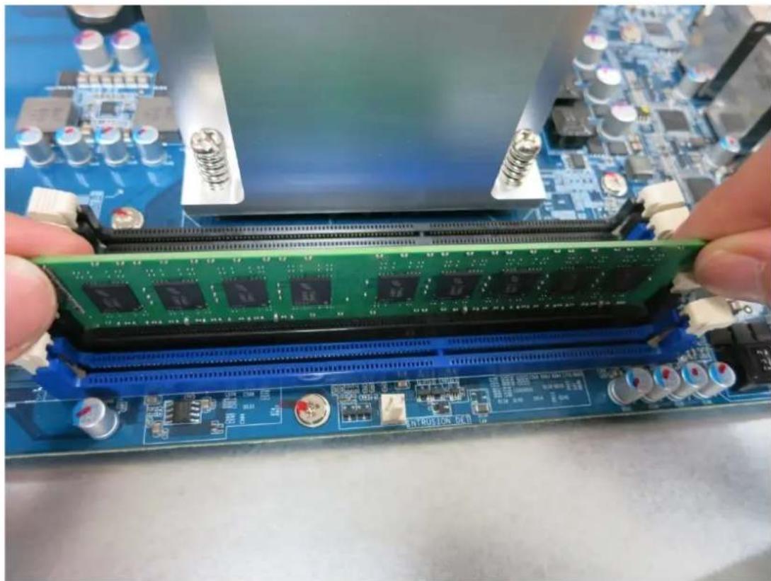 Close-up of hands installing a green and blue circuit board with multiple chips, no visible text or symbols on the components.