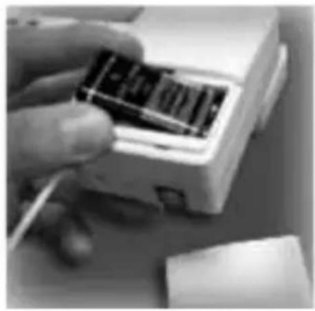 Close-up of a hand inserting into a small electronic device (no visible text or symbols)