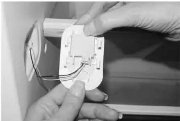 Close-up of hands installing or adjusting a white electrical socket with wires (no visible text or symbols)