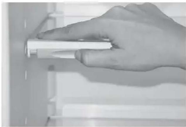 Close-up of a hand holding a white cylindrical object against a plain background (no text or symbols visible)