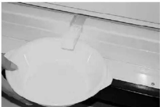 Close-up of a white circular object with a small rectangular object attached, possibly a container or basin, against a plain background (no text or symbols visible)