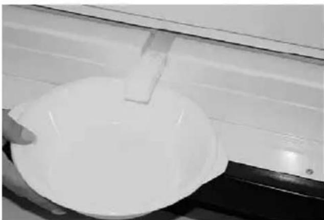 Close-up of a white circular object with a rectangular clip attached, possibly a container or basin (no visible text or symbols)
