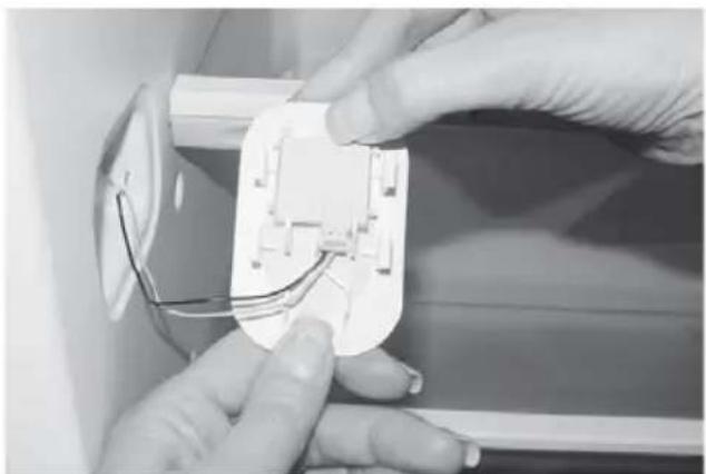 Close-up of hands installing or adjusting a white electrical socket with wires (no visible text or symbols)