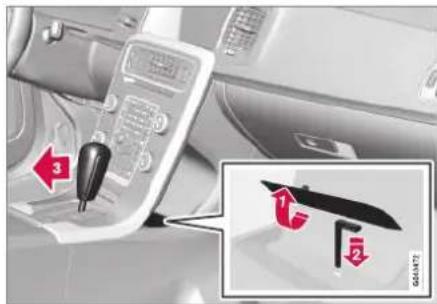 Car interior control panel with red directional arrows and a close-up of a device labeled '1' and '2' pointing to a blue clip.