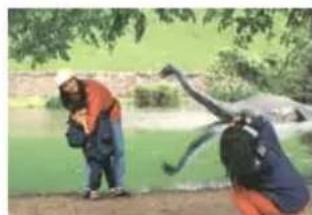 Two people outdoors near a pond, one kneeling and the other leaning forward (no visible text or symbols)