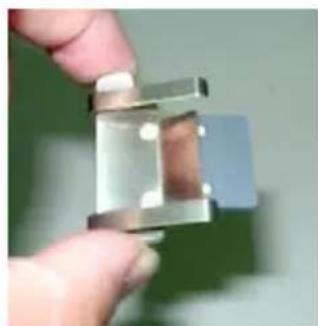 Close-up of a hand holding a metallic mechanical component (no visible text or symbols)