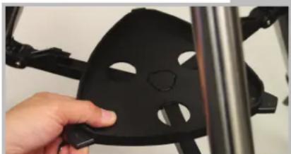 Close-up of a hand holding a black 3D-printed object with cutouts, next to a metallic frame (no text or symbols visible)