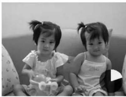 Black-and-white photo of two young girls sitting on a couch, one holding a stuffed toy (no text or symbols visible)