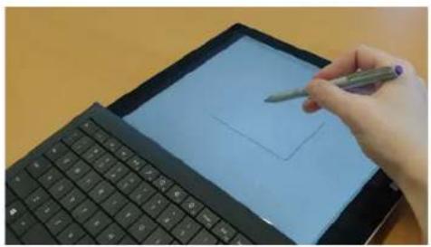 Hand drawing on a tablet screen with a stylus, placed on a keyboard (no text or symbols visible)