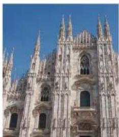 Exterior view of a Gothic cathedral facade with multiple spires and arched windows under a clear blue sky (no signage or text visible)