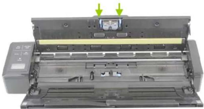 Interior view of a printer showing the lid and base with two green arrows pointing to the top panel (no text or symbols visible)