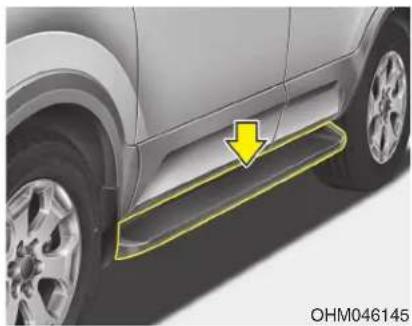 Side view of a car's front wheel and side panel, showing a yellow arrow pointing to the side panel (no text or symbols on the car itself)