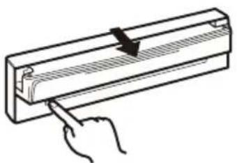 Hand inserting a button into a rectangular device with a handle (no text or symbols visible)